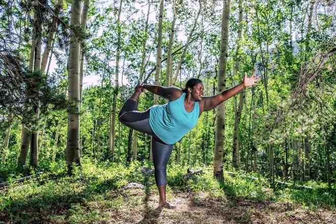 Mirna Valerio holding a yoga pose in the woods